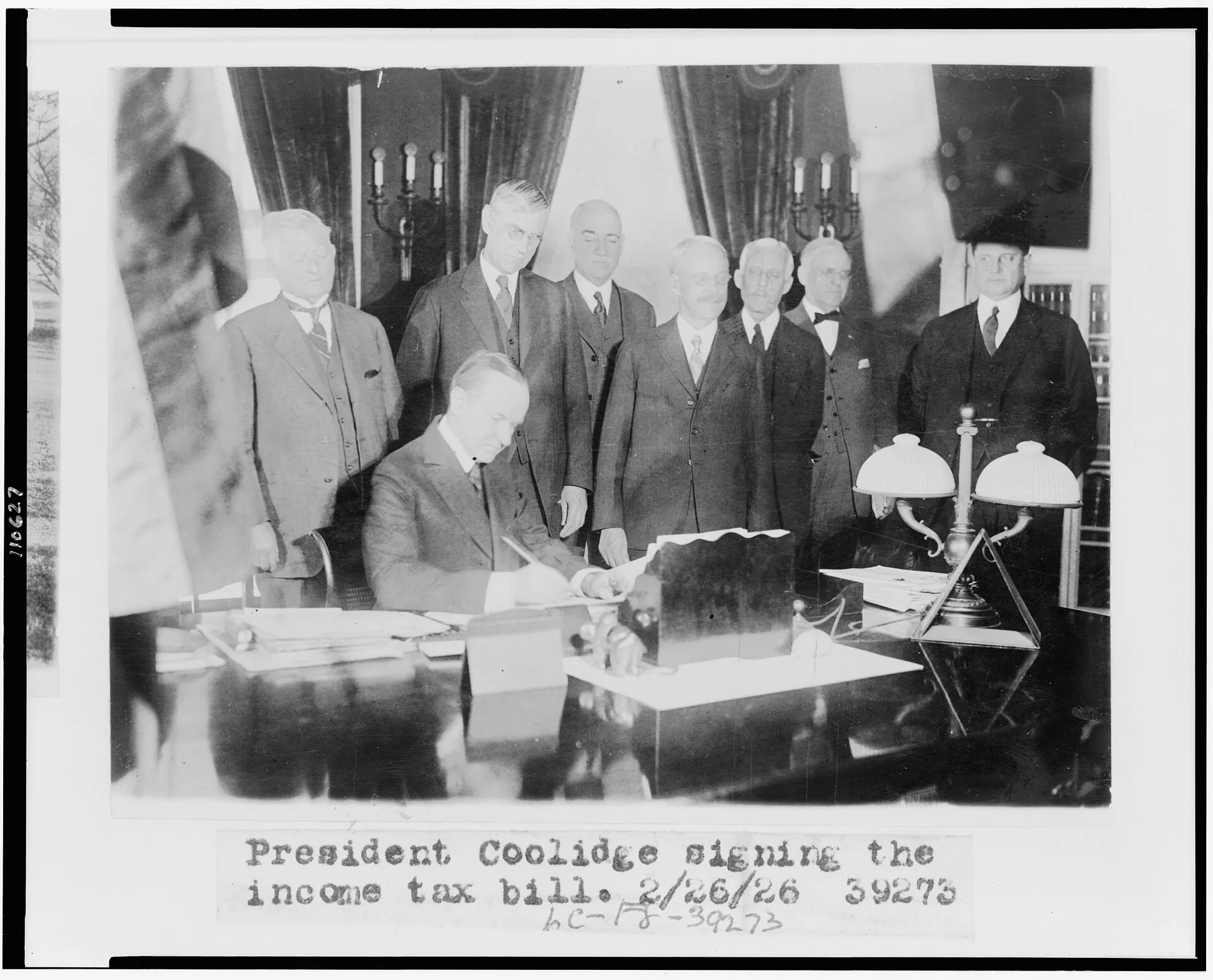 Title: Calvin Coolidge signing the income tax bill, also known as the Mellon tax bill. Secretary of the Treasury Andrew Mellon is the third figure from the right, and Director of the Budget, General Herbert Mayhew Lord, is to Mellon's left Abstract/medium: 1 photographic print. Federal business tax obligations and filing basics