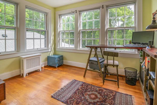 Spacious home office featuring a wooden desk, large windows, and natural light in a serene setting. Tax treatment of US home office storage under IRS rules