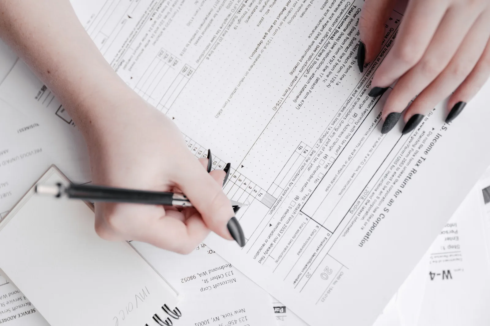 A detailed close-up of a woman filling out tax forms with a pen. Ideal for finance themes. R&D Credit and Mileage: Federal Rules for Boston and Chicago Firms